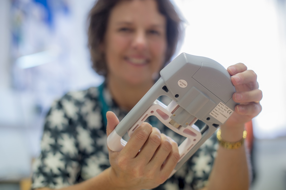 Woman smiling holding a grey device